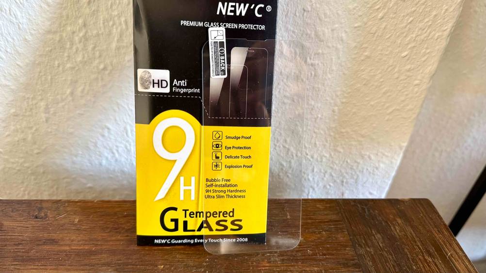 Die Verpackung und das getestete iPhone-13-Pro-Panzerglas lehnen an einer Wand.