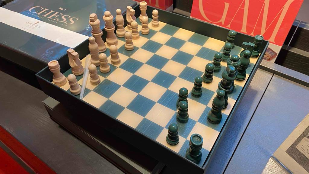 Ein getestetes Schachbrett aufgebaut, schräg von der Seite auf einer dunklen Oberfläche.