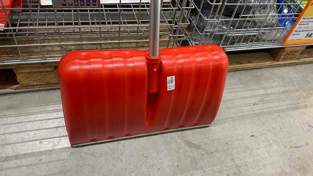 Im Test: Rückseite eines Schneeschiebers der an einem Metallkorb lehnt
