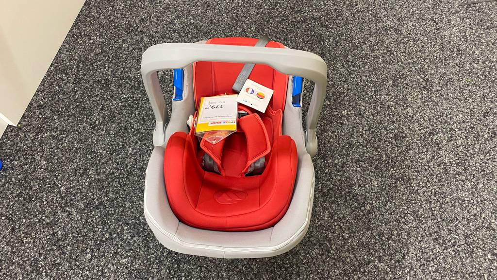 Eine getestete Babyschale von hinten oben auf einer grauen Fläche stehend.