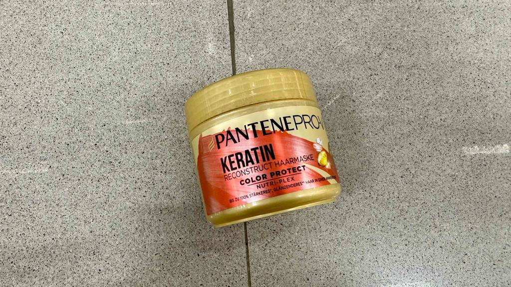Eine Packung getestete Keratin-Haarkur von Pantene Pro V ist auf einem Boden platziert.