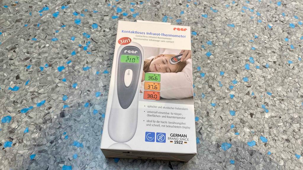 Reer-Fieberthermometer getestet: Ein verpacktes Gerät liegt auf einem graublauen Boden.
