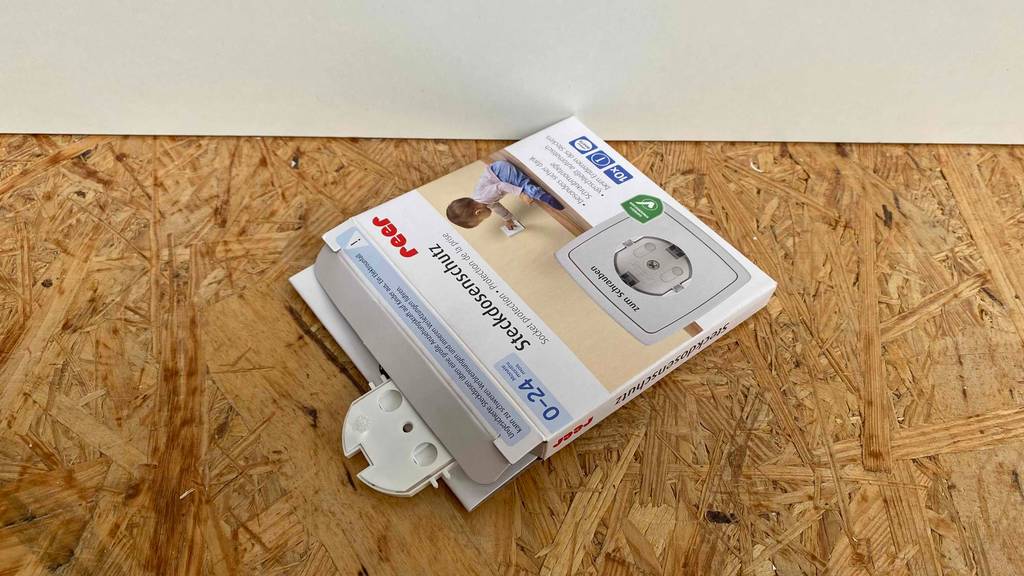 Steckdosensicherung getestet: Steckdosensicherung der Marke Reer liegend mit herausragender weißer Steckdosensicherung.