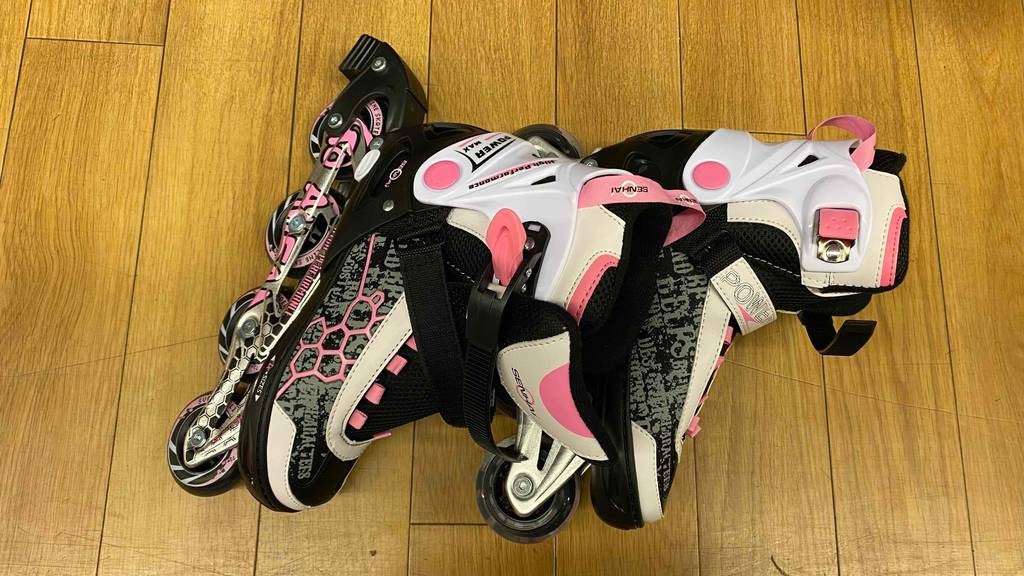 Inline-Skates für Kinder getestet: Ein Paar nebeneinander auf einem Holzboden liegend.