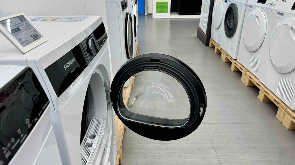 Getestet: Der Siemens-Wärmepumpentrockner steht mit geöffneter Tür im Rechtsanschlag neben weiteren Trocknern im Geschäft.