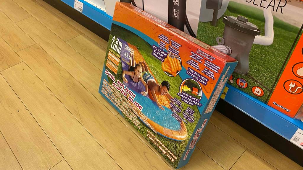 Eine verpackte Wasserrutsche lehnt an einem Regal.
