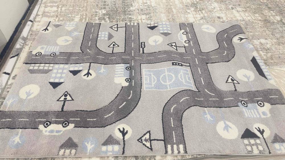 Spielteppich-Test: Ein hellgrauer Teppich mit Straßenzügen liegt ausgebreitet auf dem Boden.