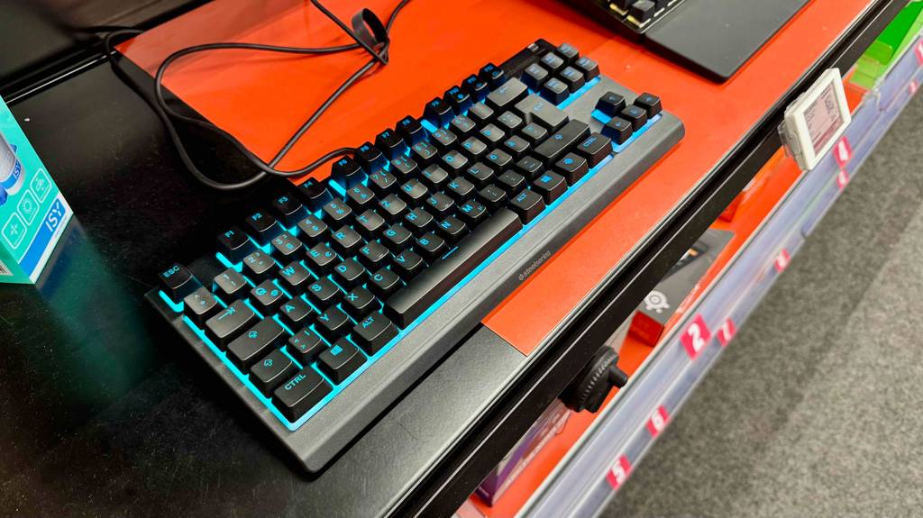 Im Test: Die türkis beleuchtete SteelSeries-Tastatur befindet sich auf einem schwarz-orangefarbenen Tisch.