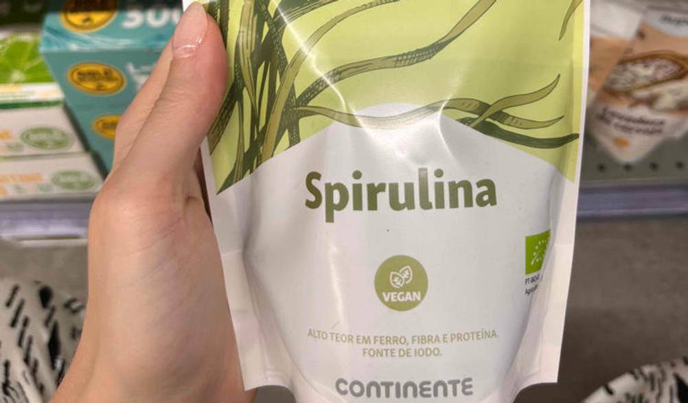 Spirulina-Test: eine Packung Spirulina der Marke Supla wird in der Hand vor einem Regal gehalten. 