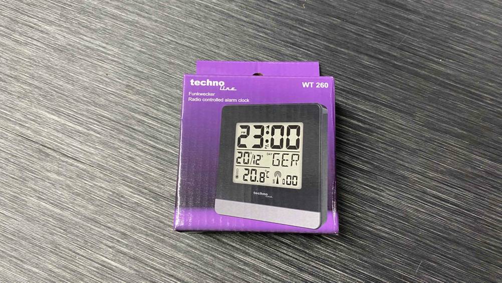 Im Test: Ein verpackter Funkwecker liegt auf einer grauen Holzfläche.