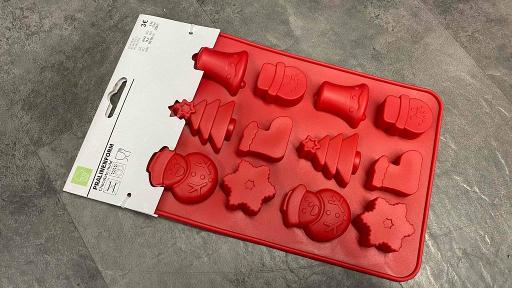 Pralinenform getestet: Eine rote weihnachtliche Form auf einem dunklen Boden.