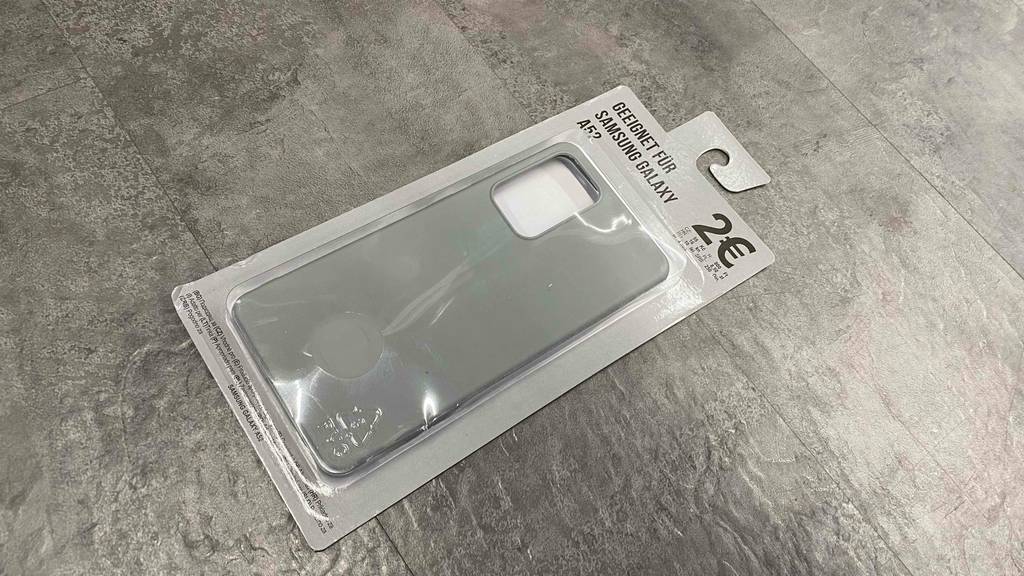 Auf einer grauen Fläche liegt eine getestete Samsung-Galaxy-A52-Hülle in Verpackung.