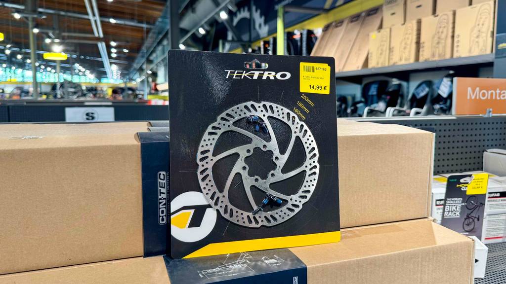 Die getestete Fahrrad-Bremsscheibe in der Verpackung steht auf einem braunen Karton im Geschäft.
