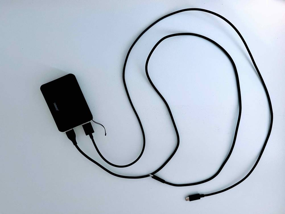 Powerbank-powerbank-10000mah getestet: Eine Powerbank mit zwei angeschlossenen Kabeln auf einer weißen Fläche liegend.