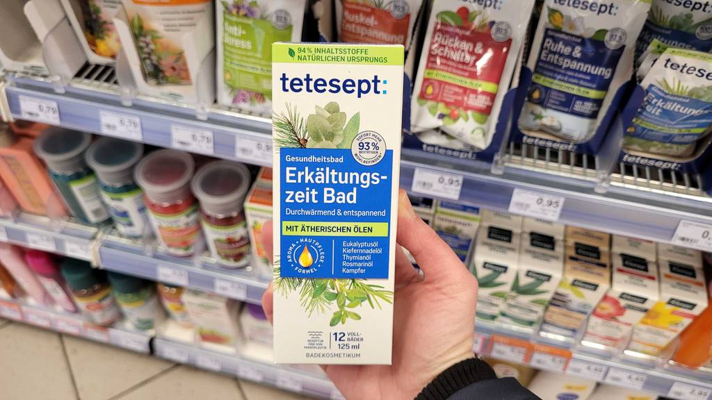 Die Verpackung des getesteten Erkältungsbads wird vor dem Regal in der Hand gehalten.