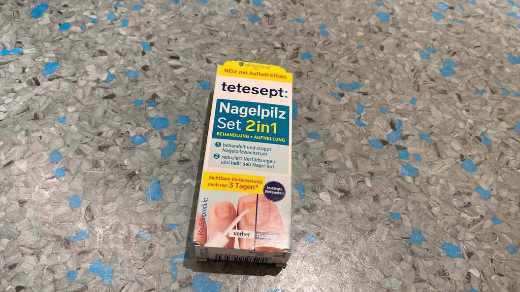 Mittel gegen Nagelpilz getestet: Eine Packung liegt auf einem blaugrauen Boden.