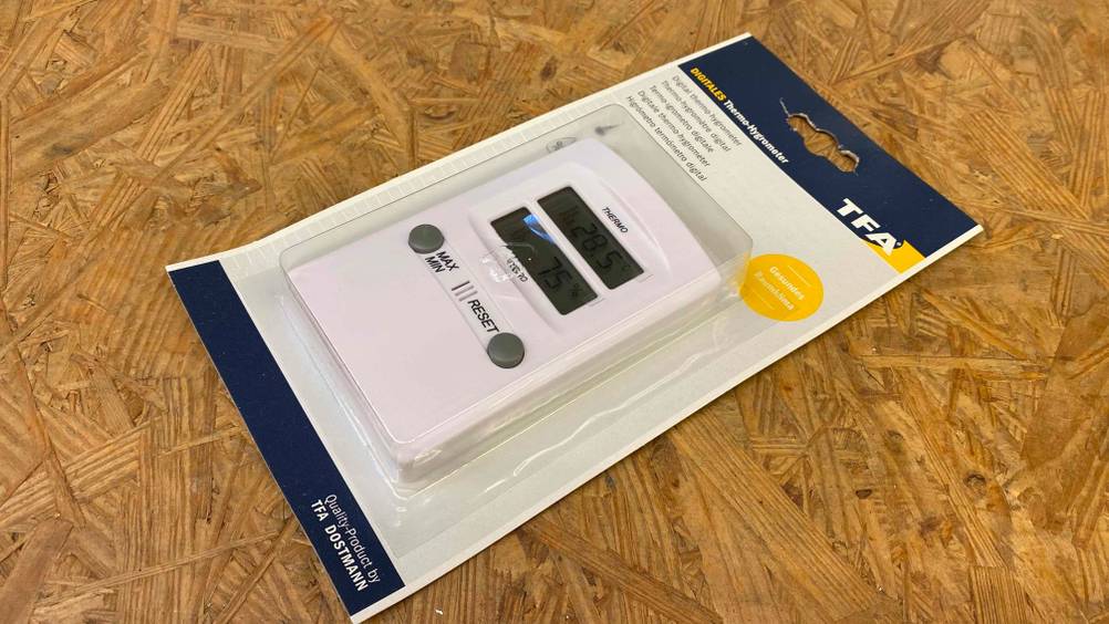Hygrometer getestet: Ein verpacktes Gerät liegt quer auf einer Holzoberfläche