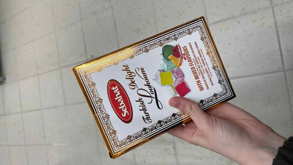 Die getesteten türkischen Süßigkeiten werden in einer Papierverpackung in der Hand gehalten.