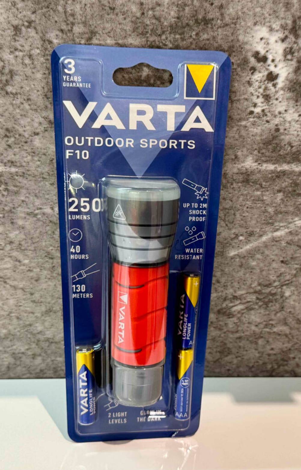 Im Test: Die Varta-Taschenlampe steht innerhalb der Verpackung vor einer grauen Wand.
