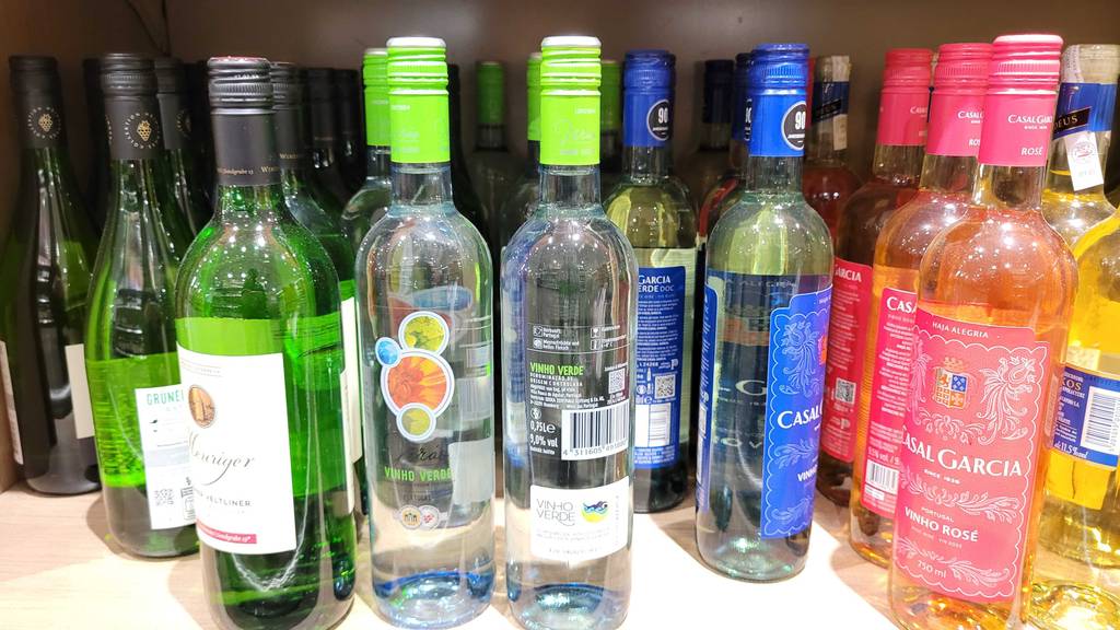 Mehrere alkoholische Getränke stehen in einem Regal, worin sich auch der Vinho Verde befindet.