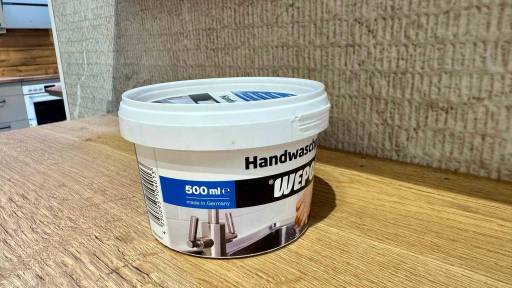 Im Küchenbereich steht die getestete Handwaschpaste im Tiegel der Marke WEPOS auf einer Holzfläche.