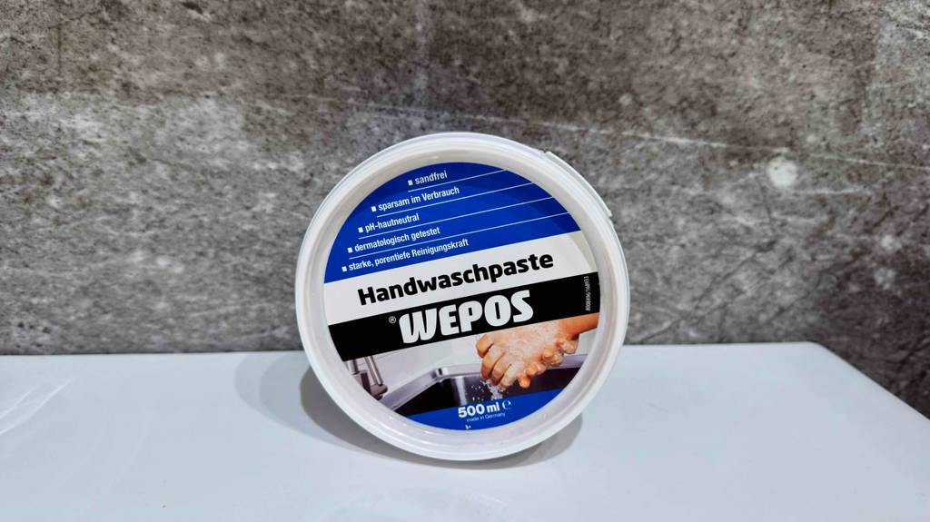 Getestet: Die Handwaschpaste im Tiegel der Marke WEPOS lehnt mit Blick auf den Deckel an einer Marmorwand.
