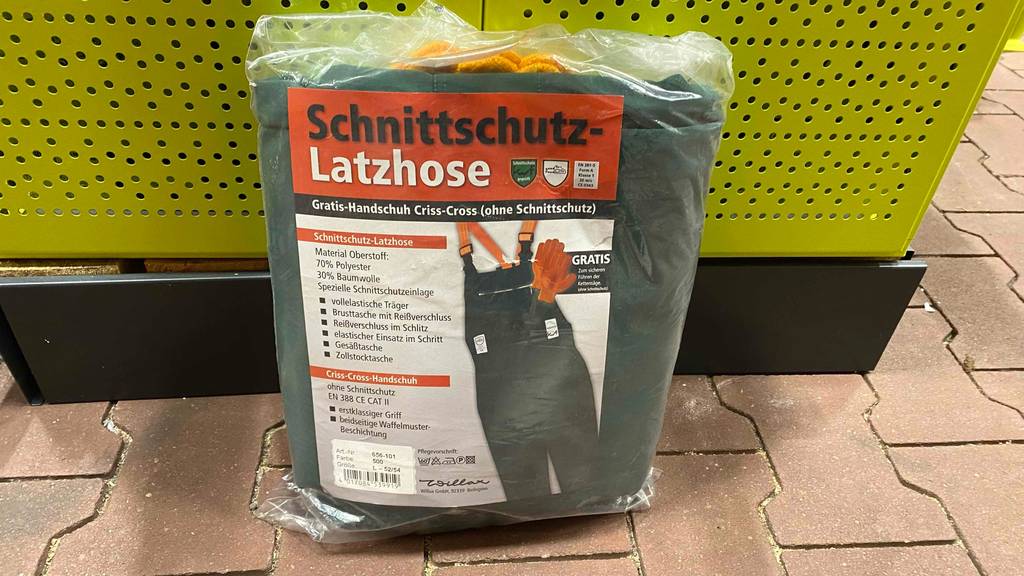Schnittschutzhose im Test: eine Schnittschutzhose mit Handschuhen inbegriffen steht aufrecht angelehnt in einem Geschäft.