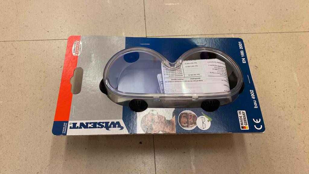 Schutzbrille getestet: Eine Brille in Originalverpackung auf Fließenboden