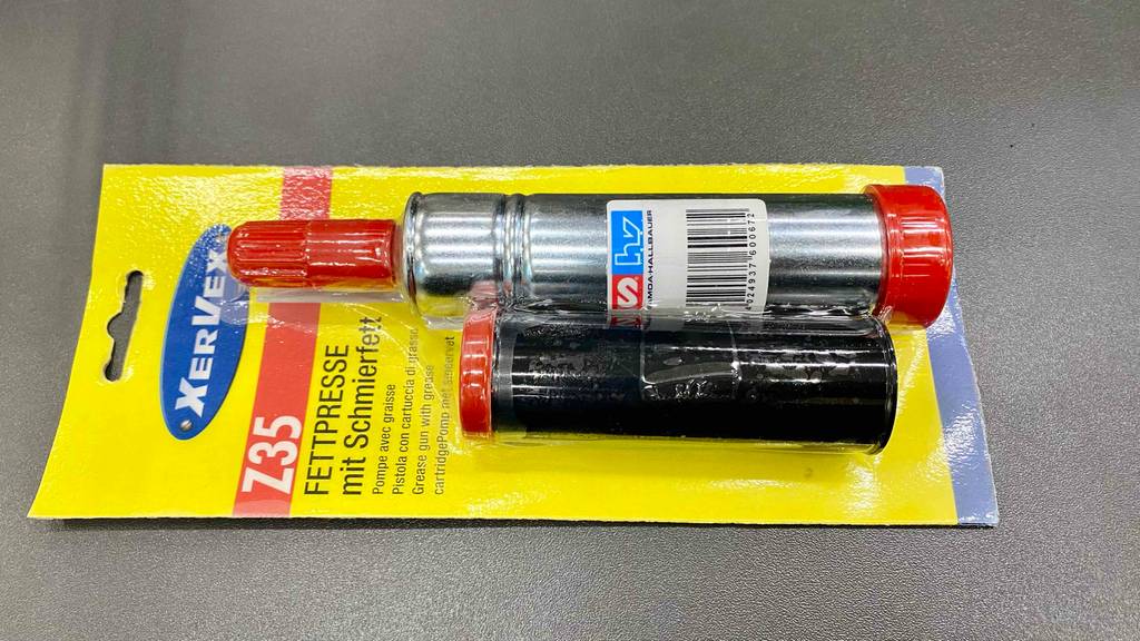 Fettpresse getestet: eine Fettpresse mit einem Schmirfett in der Originalverpackung auf einer grauen Fläche liegend.