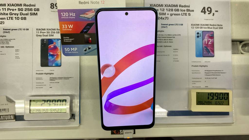 Xiaomi-Handy-Test: eingeschaltetes Xiaomi-Handy mit digitalem Preisschild daneben.