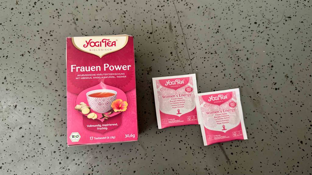 Zwei Teebeutel des getesteten Yogi Tees Frauen Power liegen neben seiner roten Verpackung.