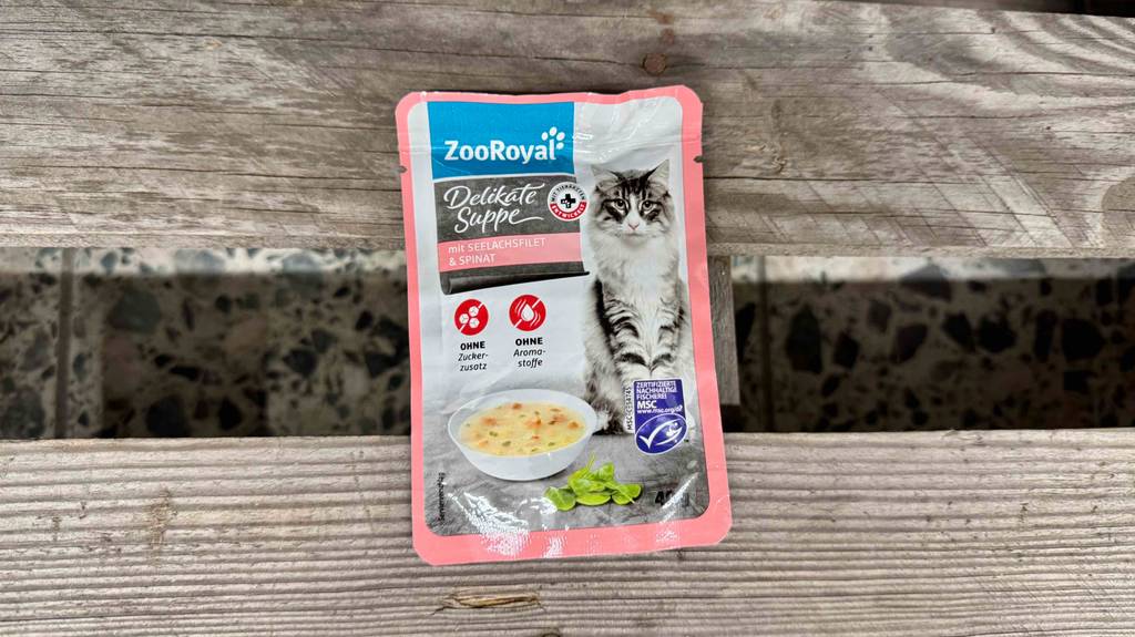 Eine getestete Katzensuppe mit Seelachs und Spinat liegt auf einer Bank.