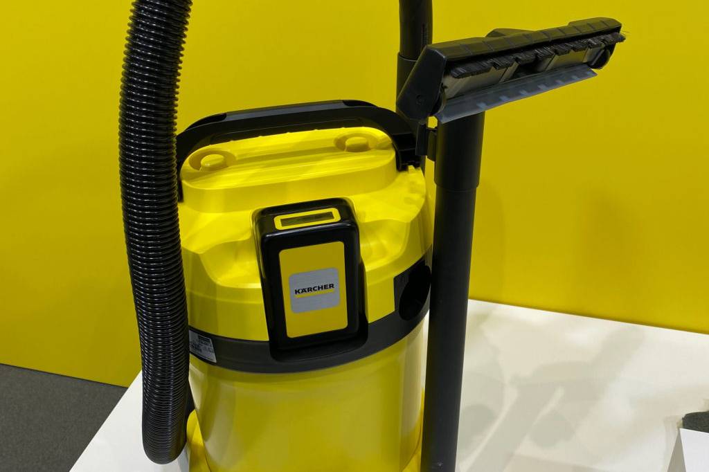 Wasserstaubsauger-Test: seitliche Gesamtansicht von stehendem, gelben Wasserstaubsauger mit Saugschlauch, Öffnungsgriff, eingesteckte Saugdüse und Saugschlauch.