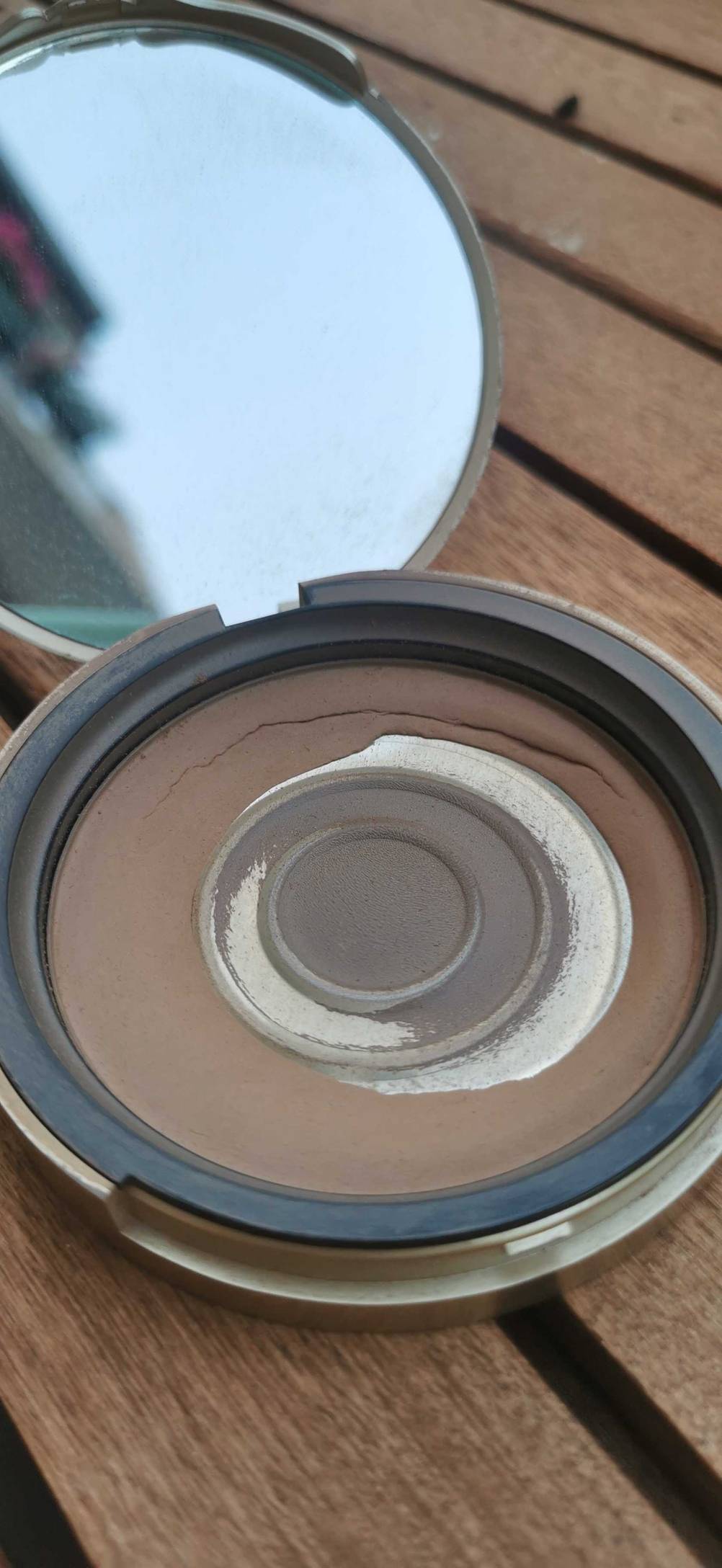 Bronzer getestet: Eine Dose geöffnet mit Spiegel auf einer Holzoberfläche.
