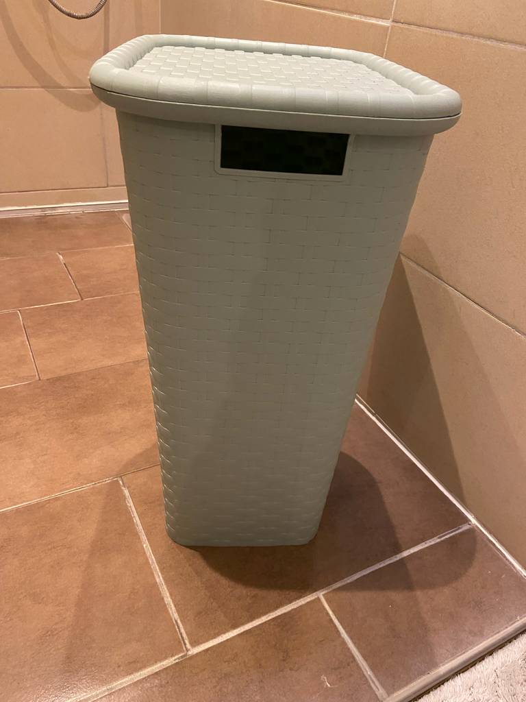 Der hellgraue getestete Wäschesammler aus einem Materialgeflecht steht in einem Badezimmer.