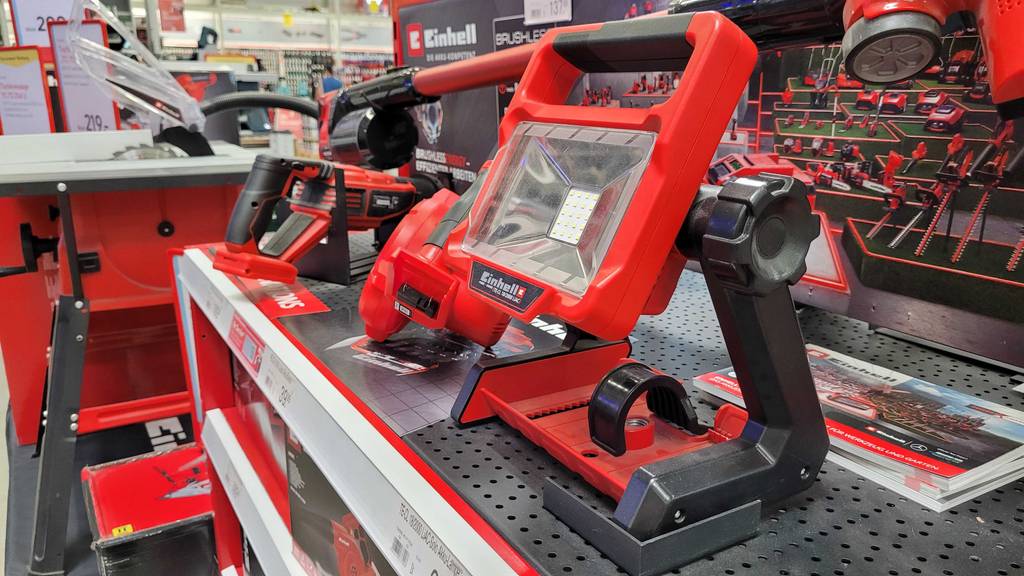 Seitenansicht eines Arbeitsscheinwerfers, der zum Testen zwischen anderen Geräten auf einer Testfläche steht.