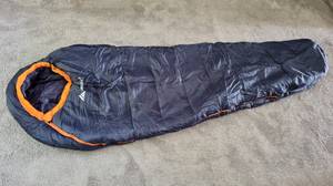 Ein ausgebreiteter, dunkelblauer Schlafsack liegt auf dem Boden. 
