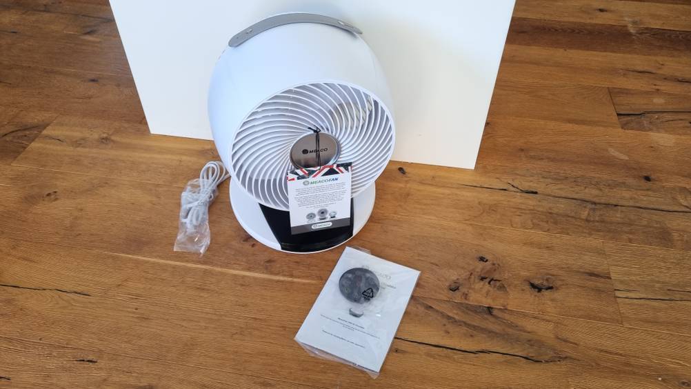 Ein weißer Ventilator mit Handbuch auf dem Boden. 