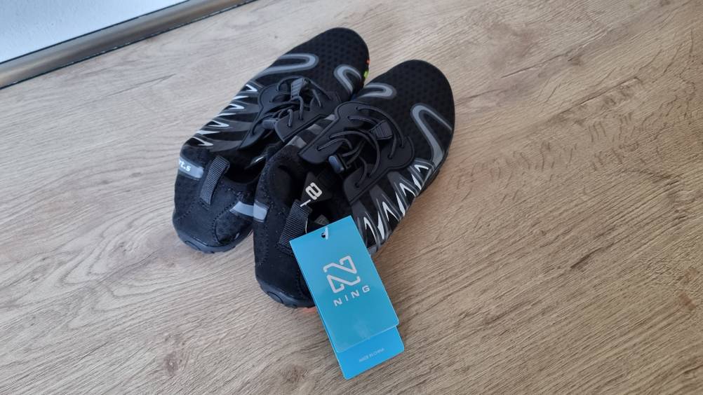 Ein schwarzes Pärchen Badeschuhe auf dem Boden liegend. 