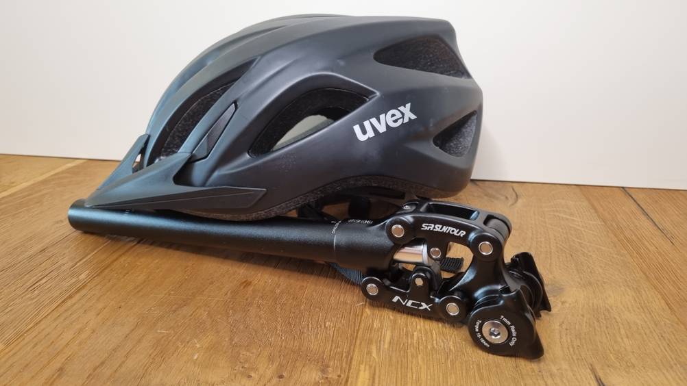 Eine gefederte Sattelstütze neben einem Fahrradhelm.