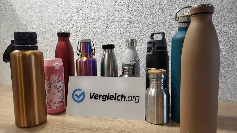 Trinkflaschen aus Edelstahl stehen hinter einem Schild mit der Aufschrift Vergleich.org