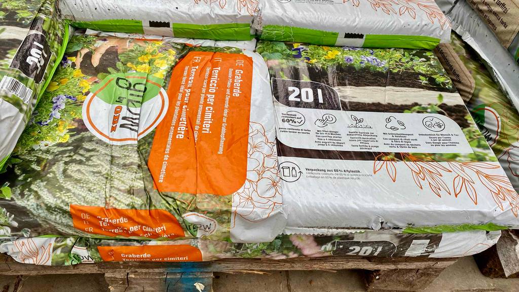 Ein 20-Liter-Kunststoffsack inklusive Graberde im Test liegt auf weiteren Graberde-Säcken auf einer Holzpalette.