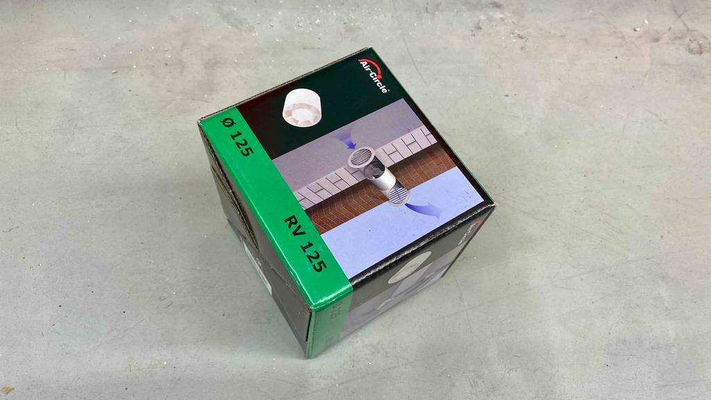 Rohrventilator getestet: Ein verpacktes Gerät liegt quer auf einem grauen Boden.