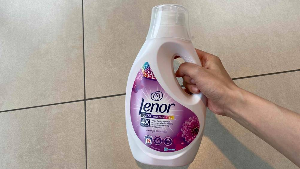 Flüssigwaschmittel im Test: Eine Hand hält eine Flasche Waschmittel vor einen hellen Hintergrund
