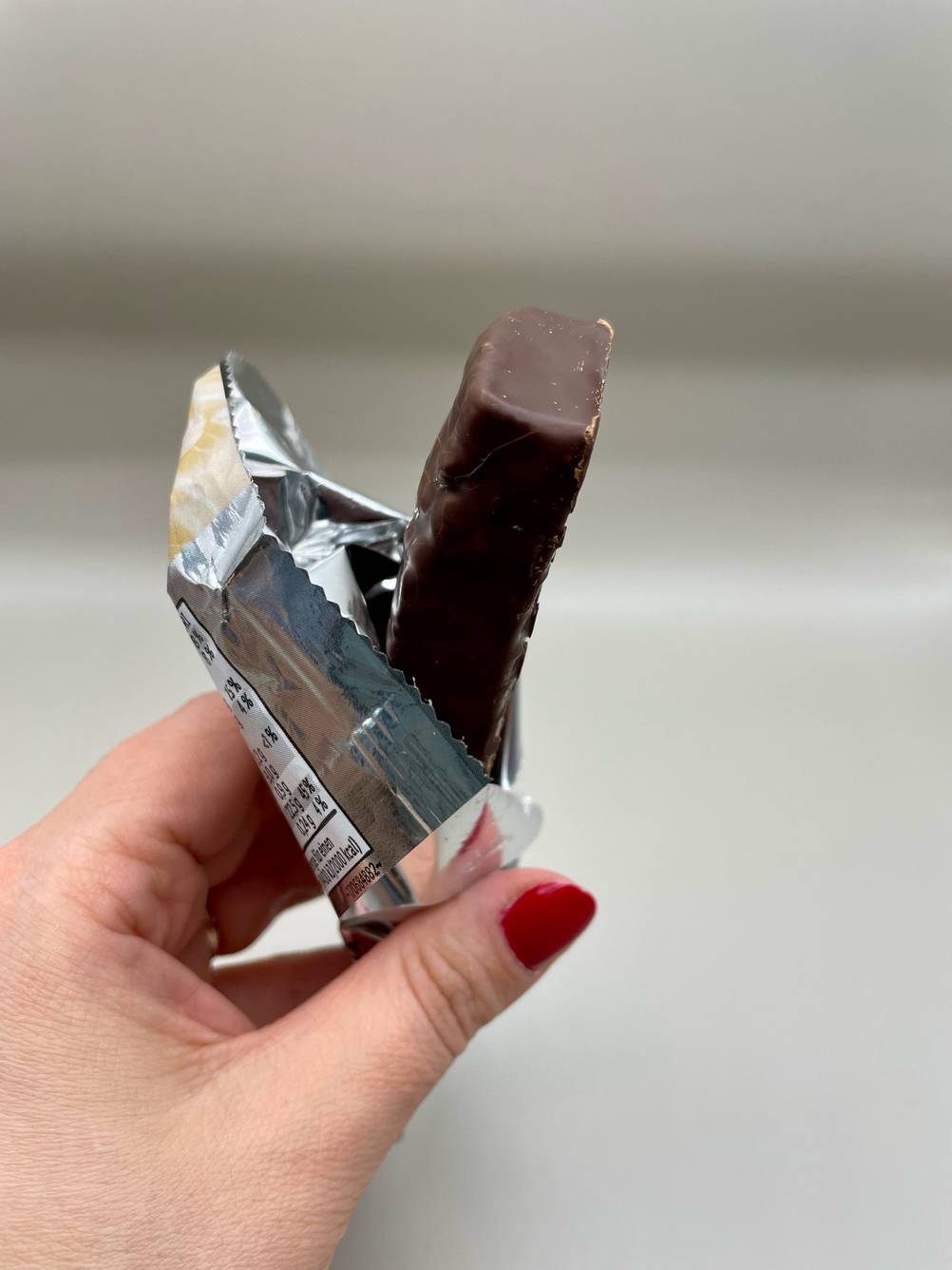 Weider-Proteinriegel-Test: geöffneter Proteinriegel, der in der in der Verpackung in der Hand gehalten wird.