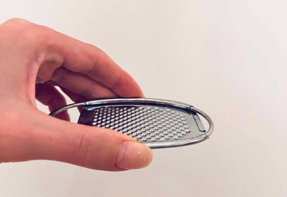 Zester-Reibe-Test: Zester-Reibe wird in der Hand vor einer weißen Wand gehalten.
