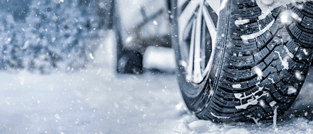 215/50-R18-Winterreifen im Test: Ein Fahrzeug steht im Schnee, der Hinterreifen in Nahaufnahme