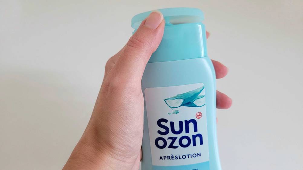 Im Test: Nahaufnahme, wie eine Hand eine Flasche After-Sun vor eine helle Fläche hält.