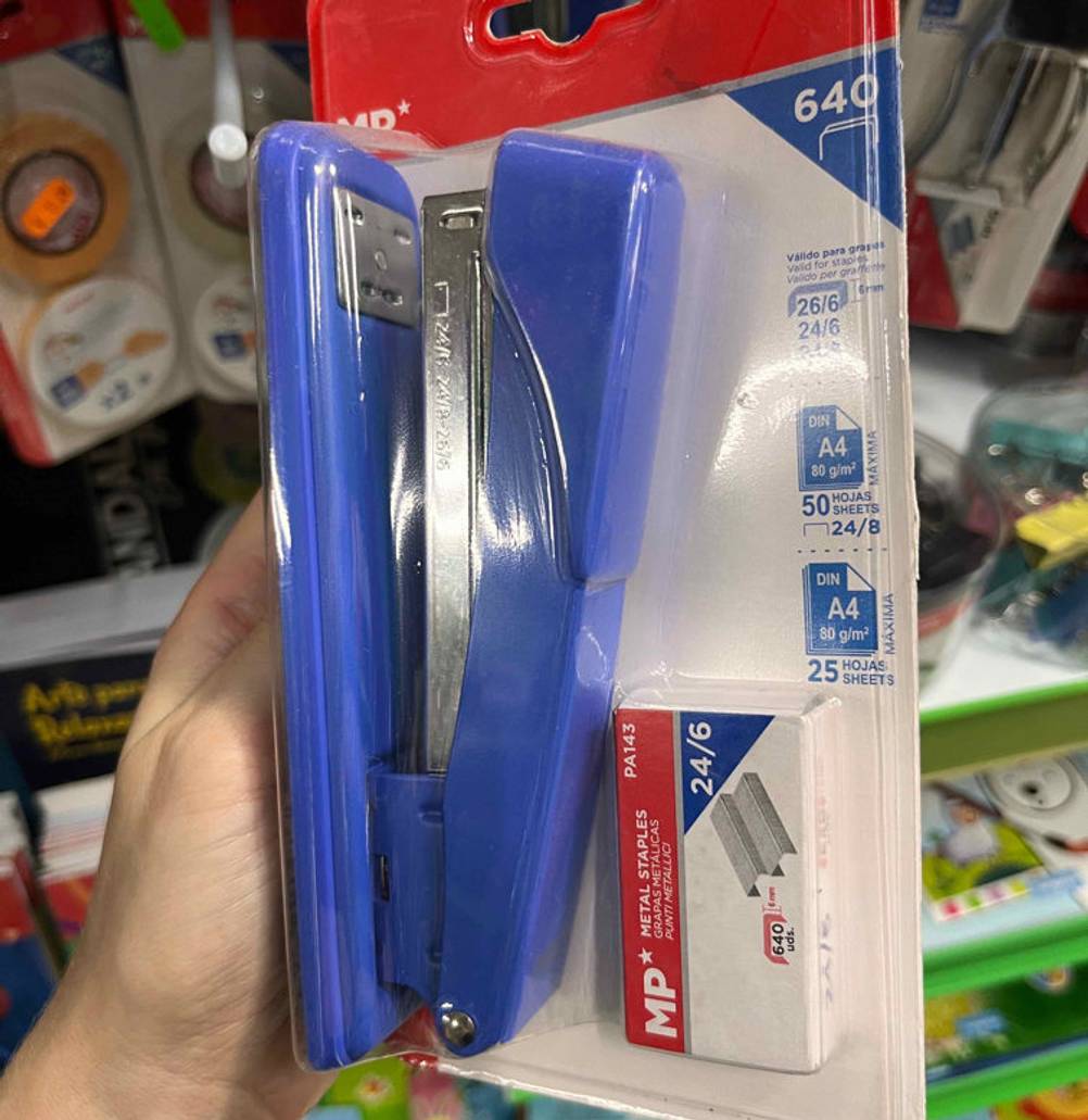 Tacker im Test: Eingepackter, blauer Tacker wird in der Hand gehalten vor einem Regal.