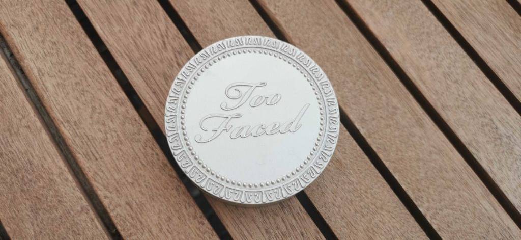Verschlossener getesteter Bronzer liegt auf Holztisch.